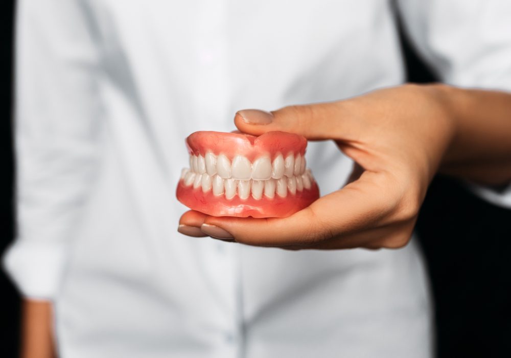 Dental prosthesis in the hands of the doctor close-up. Front view of complete denture